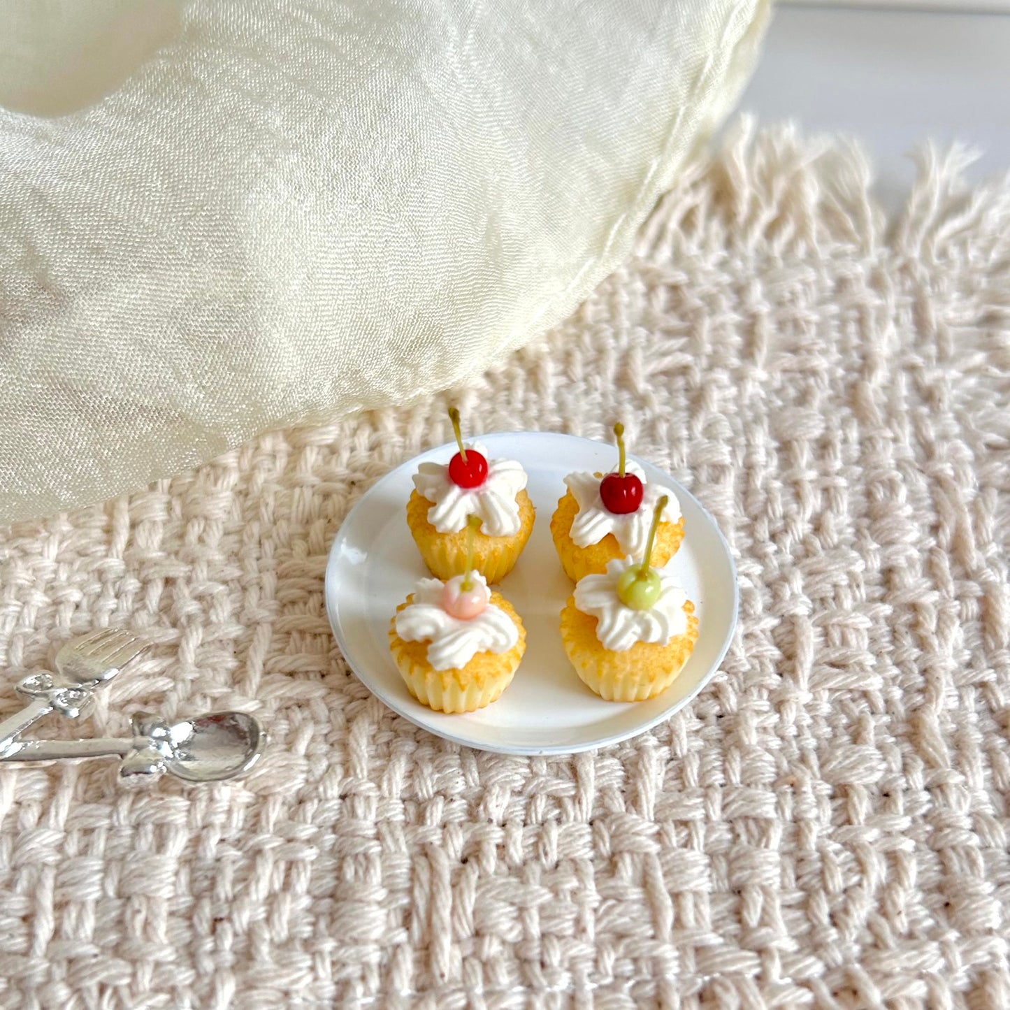 miniature cupcakes with cream topping and four cherry color styles